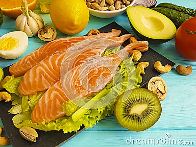 Red fish, avocado, organic nuts on a blue wooden background, healthy food fresh Stock Photo