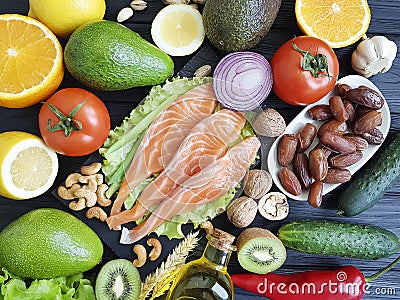 Red fish, avocado nuts selection dinner cucumber on black wooden, healthy food Stock Photo