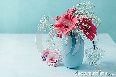 Red flowers in vase with women perfume over blue background Stock Photo