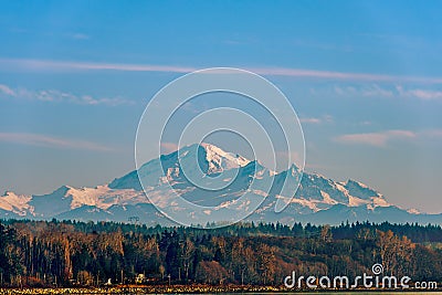 Red forest and snow-capped mountains against the blue sky, a stone river bank and a green river Stock Photo