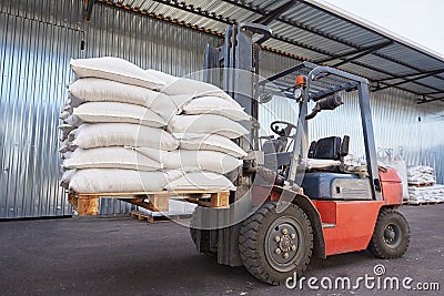 Red forklift lifts pallet with heavy bags Stock Photo