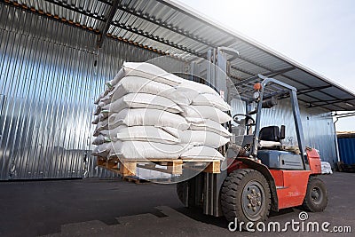 Red forklift lifts pallet with heavy bags Stock Photo