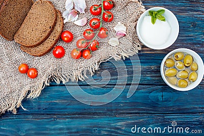 Red fresh cherries, cheese, garlic, olives in bowl, bread on dark rustic wooden background. Flat Lay with no people. Stock Photo