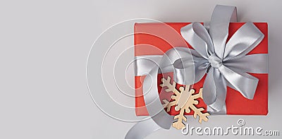 Red gift box with grey ribbon and wooden snowflake on it Stock Photo