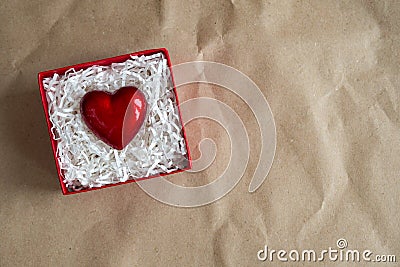 Red gift box with heart by Valentine`s day on craft paper. Giving heart love concept, copy space Stock Photo