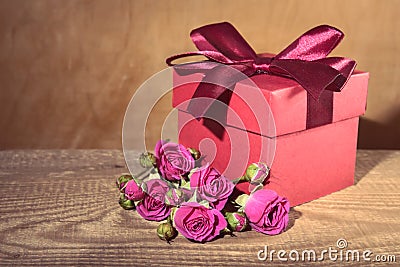 Red gift box tied with decorative ribbon and bouquet rose flower Stock Photo