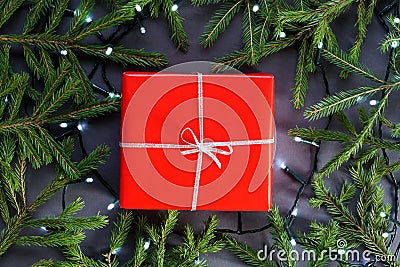 Red gift paper, box with silver ribbon, led garland and fir tree branches around Editorial Stock Photo