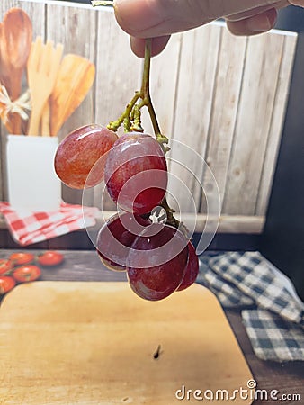 red grapes being held in hand background wood Stock Photo