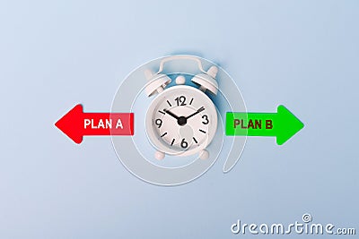 Red and green arrows with text Plan a vs plan b. Concept of choice. Two Arrows and White alarm clock on blue background, top view Stock Photo