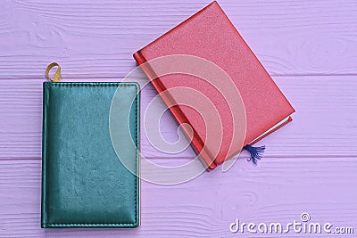 red and green leather notebooks lie on a pink table Stock Photo