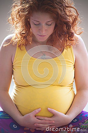 Red hair young pregnant woman hold her belly indoor shot Stock Photo