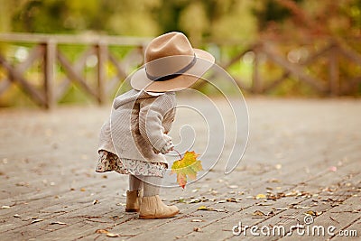 Red-haired baby girl wearing a hat outdoors in autumn Stock Photo