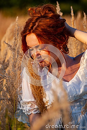 red-haired beautiful girl sits with her back in black, long dress in the grass Stock Photo