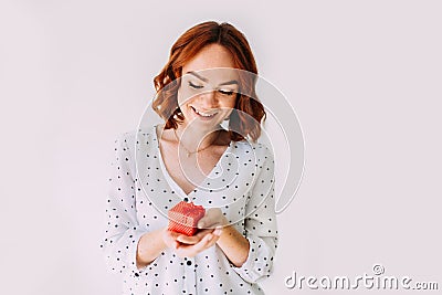 Red-haired birthday girl smiles, holding a small red gift box. Stock Photo