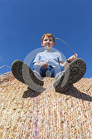 red-haired boy sitting on a golden stack Stock Photo