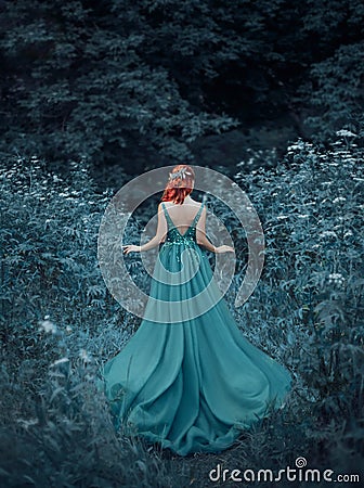 Red-haired girl in a blue, sapphire, luxurious dress in the floor, with an open back and a long train. The princess Stock Photo