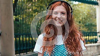 Ginger girl listening to music in big headphones Stock Photo