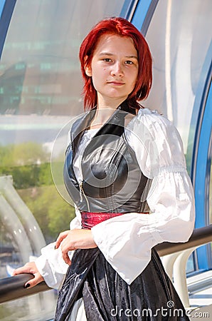 Red-haired girl in a long dress walks on the bridge Stock Photo