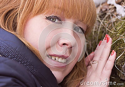 The red-haired girl touches the moss on the stone. Stock Photo