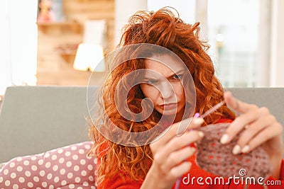 Red-haired needlewoman feeling thoughtful about chosen color Stock Photo