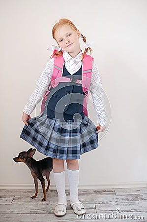 Schoolgirl with a pink briefcase and dog indoors Stock Photo