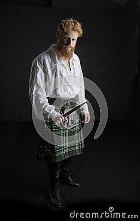 Red-haired Scotsman posing with a sword Stock Photo