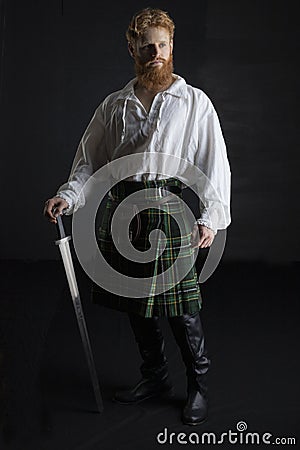 Red-haired Scotsman posing with a sword Stock Photo