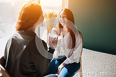 Red-haired two young women are talking and drinking coffe. Female models loughing in a cafe Stock Photo