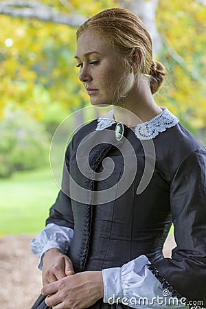 Victorian woman in black dress walking in garden Stock Photo