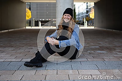 Red-haired woman with black jeans, black sweater and denim jacket in an urban location. Stock Photo