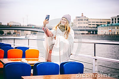 Red-haired woman in glasses traveler in a hat and jacket making a selfie in Moscow on a pleasure boat on the river in the city Stock Photo