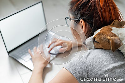 Red-haired woman in isolation lying on the floor with a dog. The girl maintains a social distance and works from home on Stock Photo