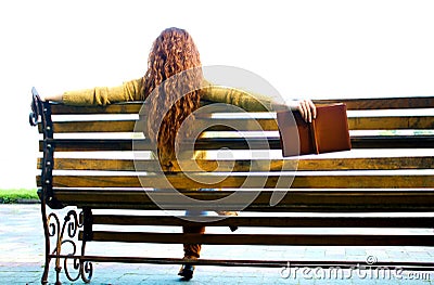 Red - haired woman sitting on bench with book Stock Photo