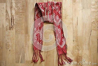 Red handmade weaving scarf in wooden background. Stock Photo