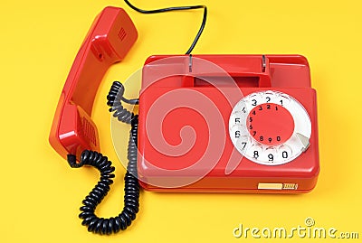 A red handset lies next to a landline telephone on a yellow background. An old Soviet vintage telephone. Stock Photo