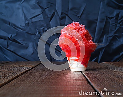 Red Hawaiian Shave ice, Shaved ice or snow cone dessert in a clear flower cup against a black background. Stock Photo