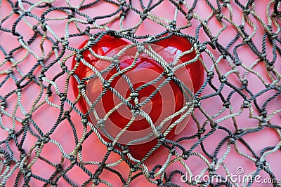 Red heart covered with mesh. concept of rejection of love, prohibition of free expression of emotions, concept of constraint , Stock Photo