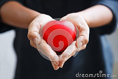 Red heart held by female`s both hands, represent helping hands, caring, love, sympathy, condolence, customer relationship, patient Stock Photo