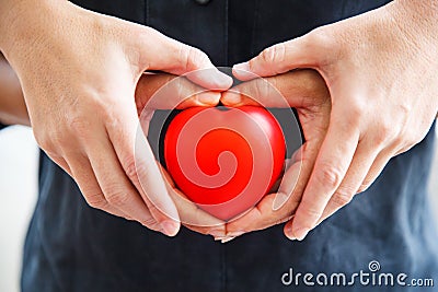 Red heart held by male and female`s both hands, represent helping hands, help each other, love, partnership, sympathy, customer an Stock Photo