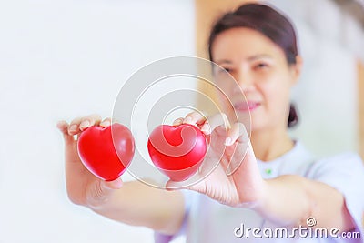 Red heart held by smiling female nurse`s hand, representing giving effort high quality service mind to patient. Professional Stock Photo