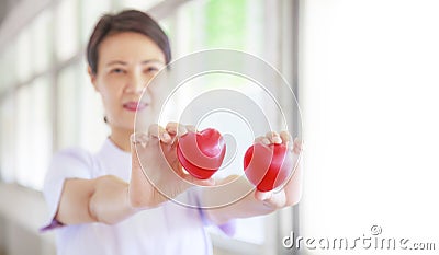 Red heart held by smiling female nurse`s hand, representing giving effort high quality service mind to patient. Professional, Spe Stock Photo
