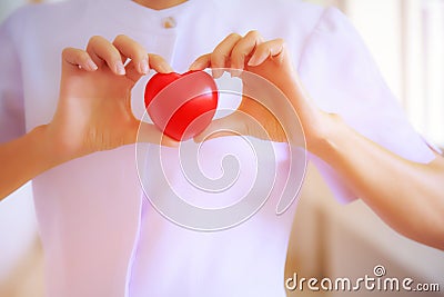 Red heart held by smiling female nurse`s hand, representing giving effort high quality service mind to patient. Professional, Spec Stock Photo