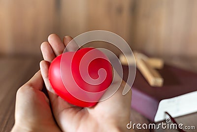 A red heart symbol on hand and a cross on the Scriptures. A blessing from God with the power and power of holiness, which brings Stock Photo