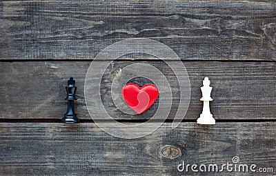 Red heart between two chess kings on rustic wood Stock Photo