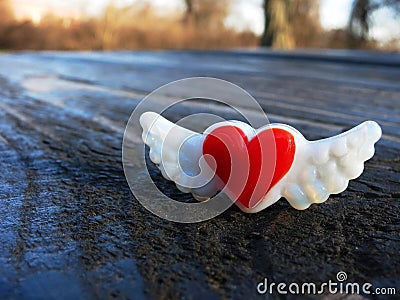 Red heart with wings magnet on picnic table. Stock Photo