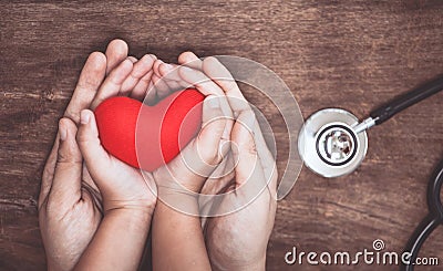 Red heart on woman and child hands and with doctor`s stethoscope Stock Photo