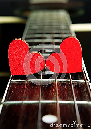 Red hearts on the strings of a guitar. Hearts are a symbol of love. Valentine`s Day Stock Photo