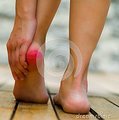 Red heel because of pain, woman hand making some massage. Wooden floor Stock Photo