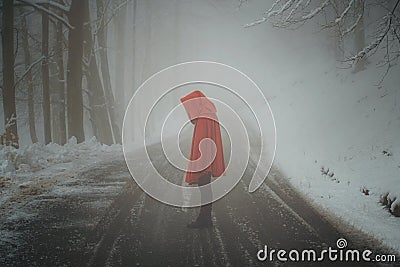 Red hooded woman in a desolate winter road Stock Photo