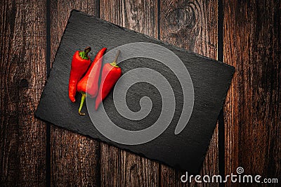 Red hot chili peppers on a slate board on a dark wooden table. Top down overhead view Stock Photo